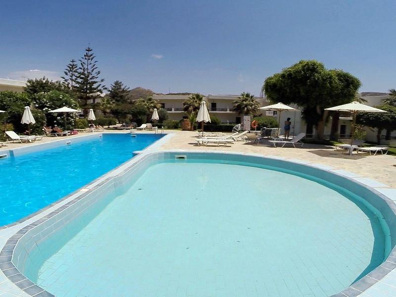 Zwei Schwimmbecken in einem sonnigen Außenbereich mit Liegestühlen und Sonnenschirmen.