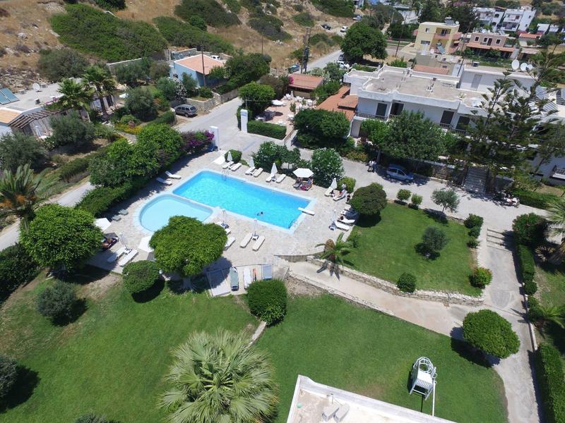 Grüner Garten mit Bäumen und Swimmingpool, umgeben von Wohnhäusern und Wegen.