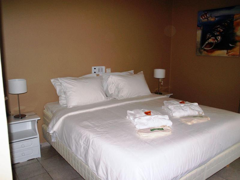 Ein schlichtes Schlafzimmer mit einem großen Bett, weißen Bettwäsche und zwei Nachttischen mit Lampen.