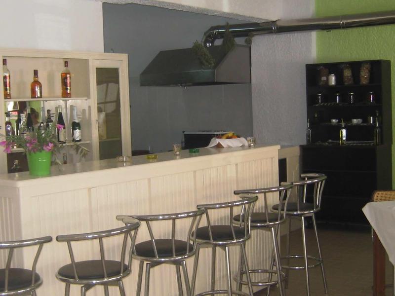 Modern hotel bar area with white counter cabinets and tall metal bar stools.