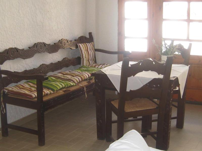 Rustic wooden table with chairs and bench in a bright room with windows.