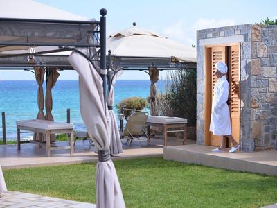 Strefa zewnętrzna hotelu z altanami, leżakami i widokiem na morze przy czystym niebie.