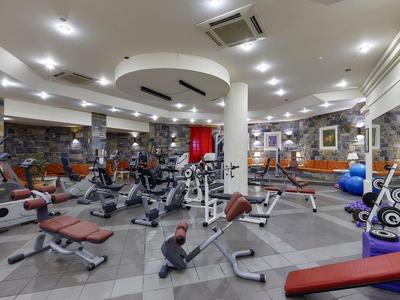 Moderner Fitnessraum mit verschiedenem Trainingsgerät, Spiegeln und hellem Licht.