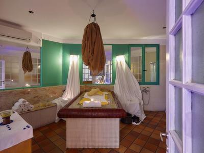 Spokojne pomieszczenie spa z wanną, świecami i miękkim oświetleniem do relaksu.