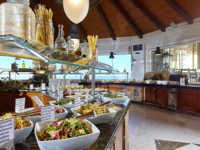 Bufet z świeżymi sałatkami i potrawami w jasnej restauracji hotelowej z drewnianym sufitem.