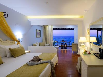 Jasno urządzony pokój hotelowy z balkonem i widokiem na morze o zachodzie słońca