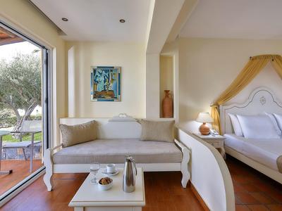 Pokój hotelowy z nowoczesną sofą, łóżkiem, widokiem na taras i ogród.