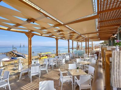 Zewnętrzny obszar restauracji z białymi krzesłami i stołami z widokiem na morze.