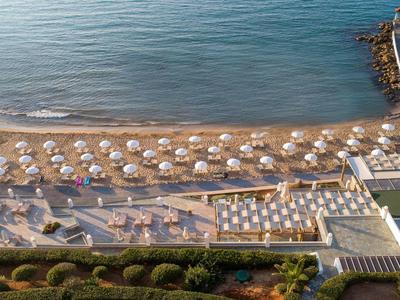 Plaża z parasolami i leżakami obok basenu i molo nad morzem.