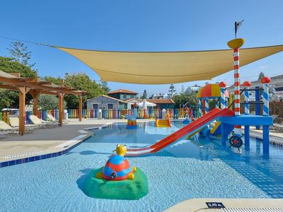 Basen dla dzieci z kolorowym placem zabaw wodnych i daszkiem przeciwsłonecznym w ośrodku hotelowym
