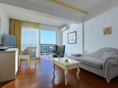 Světý obývací pokoj s pohovkou, stolem a výhledem na balkon a moře.