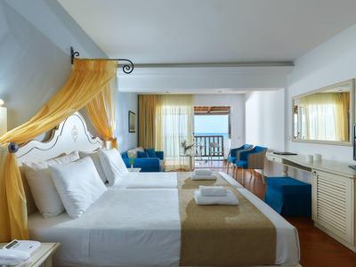 Elegancki pokój hotelowy z dużym łóżkiem, żółtym baldachimem i widokiem na balkon.