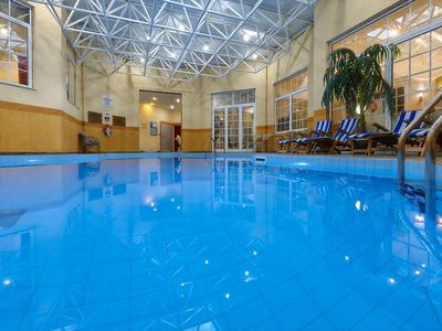 Vnitřní prostor hotelu s velkým bazénem a lehátky vedle.