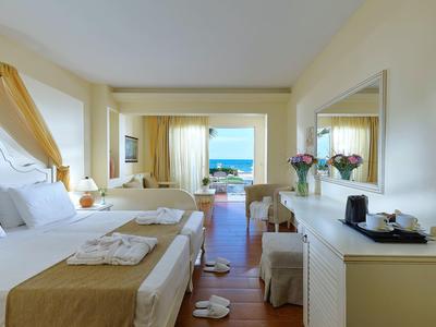 Jasny pokój hotelowy z dwoma łóżkami, widokiem na morze przez duże okno i stylowym wystrojem.