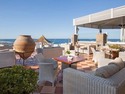 Pohodlná terasa s proutěným nábytkem a výhledem na moře pod jasnou oblohou.