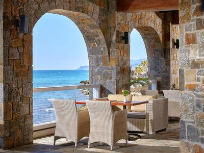 Terasa s posezením pod kamennými oblouky s výhledem na moře.