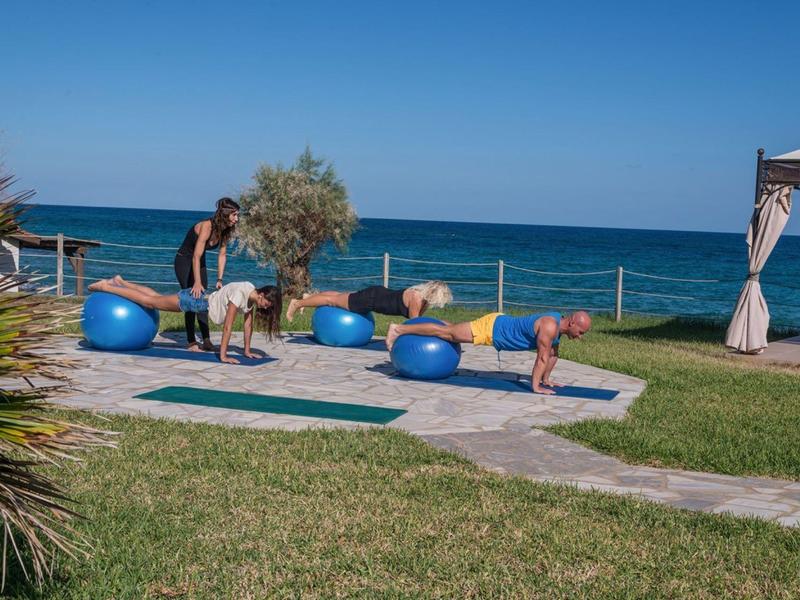 Ludzie ćwiczą jogę na świeżym powietrzu z widokiem na morze pod czystym niebem.