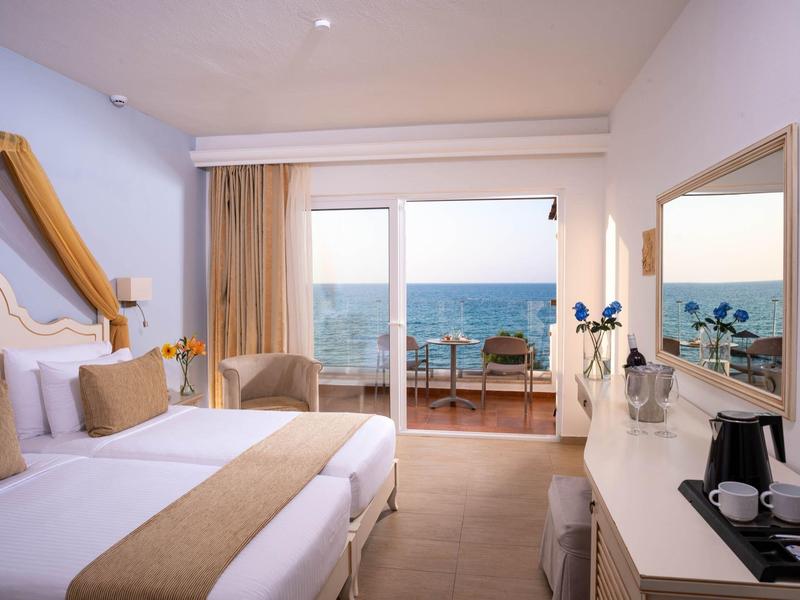 Pokój hotelowy z dwoma łóżkami pojedynczymi i widokiem na morze z balkonu.