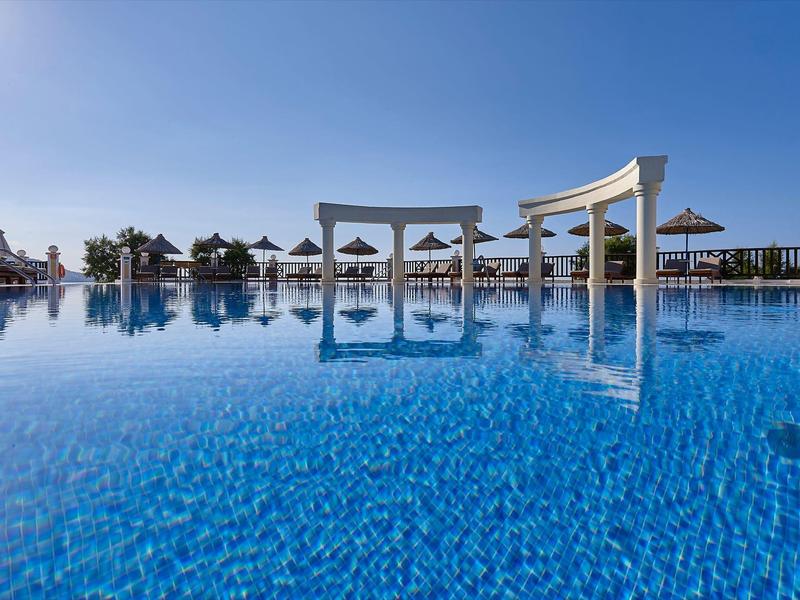 Duży basen z czystą, niebieską wodą i parasolami pod czystym niebem