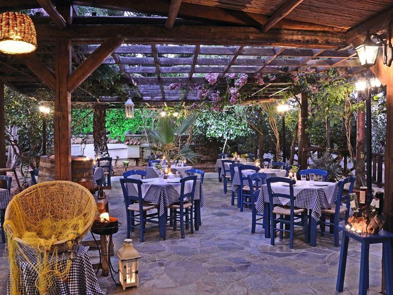 Przytulny zadaszony teren na zewnątrz restauracji z nakrytymi stołami i nastrojowym oświetleniem.