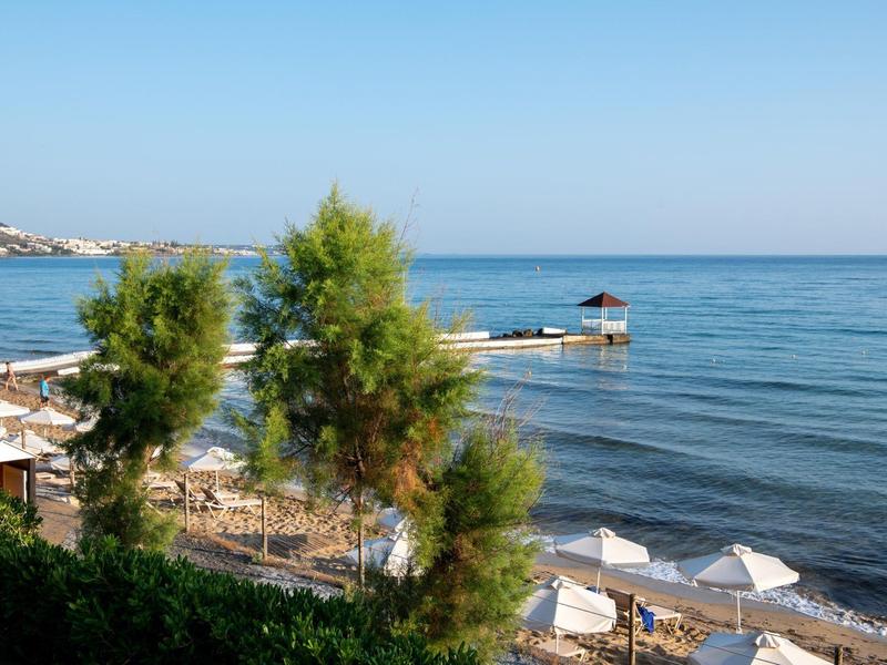 Widok na wybrzeże z leżakami, parasolami i małym drewnianym pomostem nad morzem