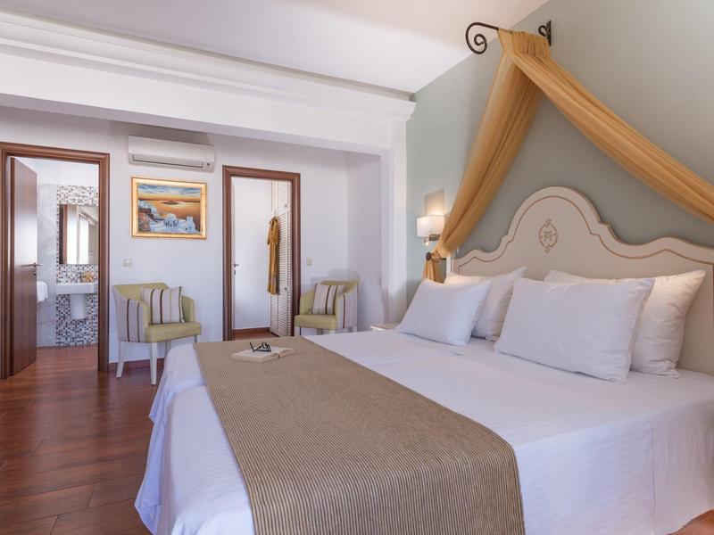 Jasny pokój hotelowy z dużym łóżkiem, miejscem do siedzenia i dostępem do łazienki