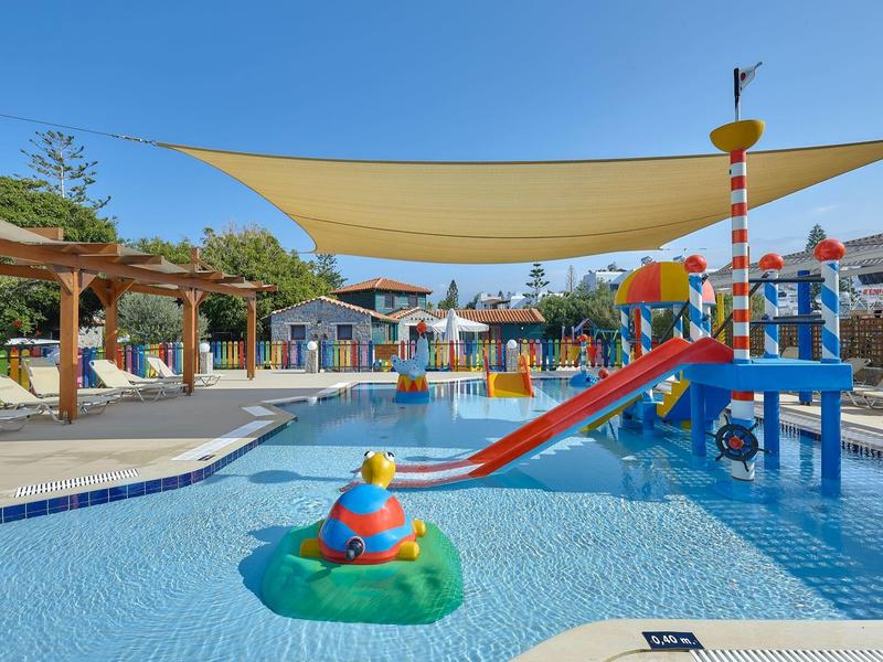 Basen dla dzieci z kolorowym placem zabaw wodnych i daszkiem przeciwsłonecznym w ośrodku hotelowym