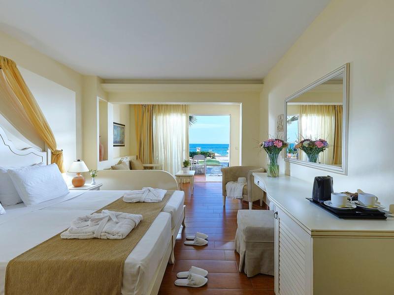 Jasny pokój hotelowy z dwoma łóżkami, widokiem na morze przez duże okno i stylowym wystrojem.