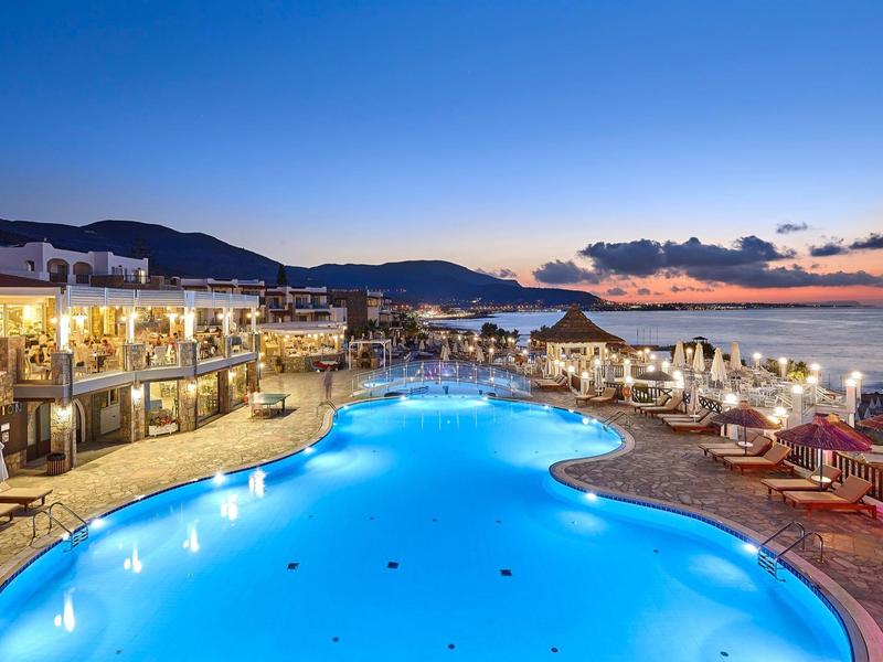 Basen hotelowy o zachodzie słońca z górami i morzem w tle