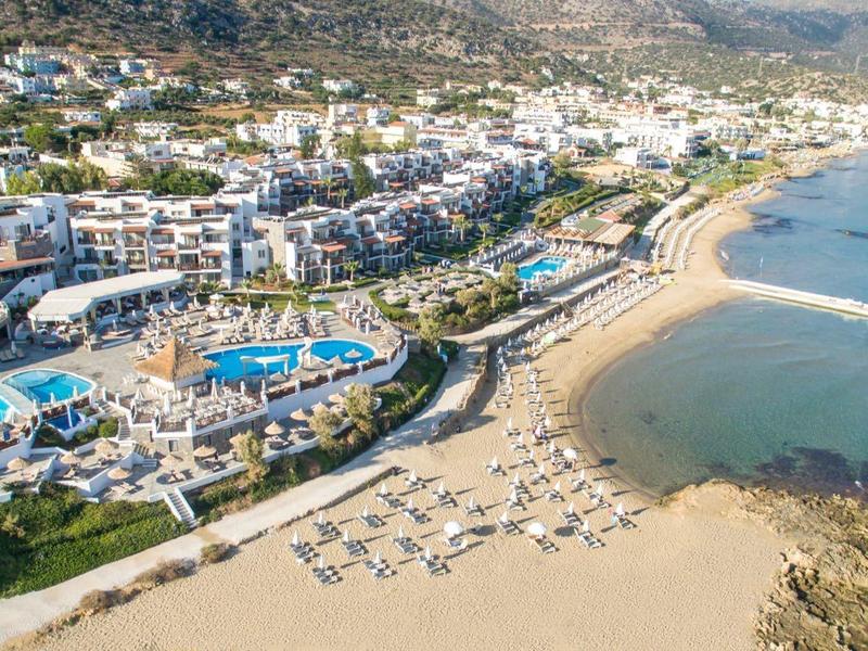 Duży kompleks hotelowy z wieloma basenami i piaszczystą plażą przy morzu.