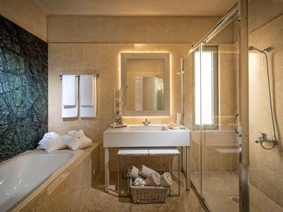 Salle de bains moderne avec baignoire, lavabo, miroir et cloison en verre pour la douche.