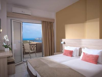 Chambre d'hôtel lumineuse avec deux lits et vue sur la mer depuis le balcon