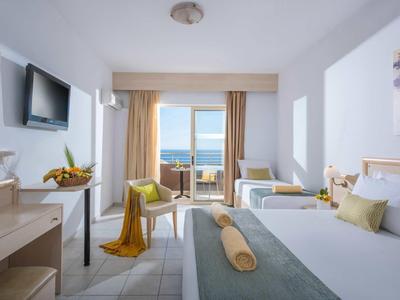 Chambre d'hôtel lumineuse avec lit double et balcon donnant sur la mer.