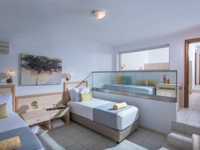 Chambre d'hôtel moderne avec deux lits simples, œuvre murale et cloison en verre.