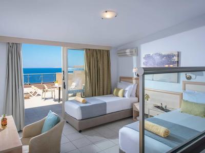 Chambre d'hôtel moderne avec deux lits, balcon et vue dégagée sur la mer.