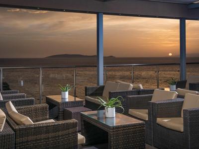 Terrasse extérieure confortable avec meubles en rotin et vue sur le coucher de soleil sur le paysage.