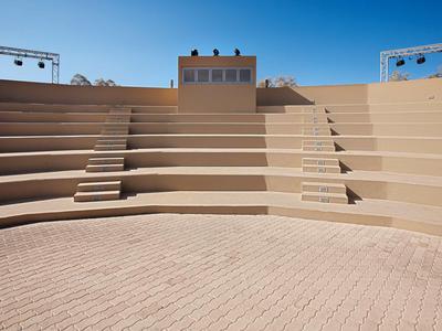 Ein rundes Amphitheater mit stufenförmigen Sitzplätzen und klarem blauem Himmel im Hintergrund.