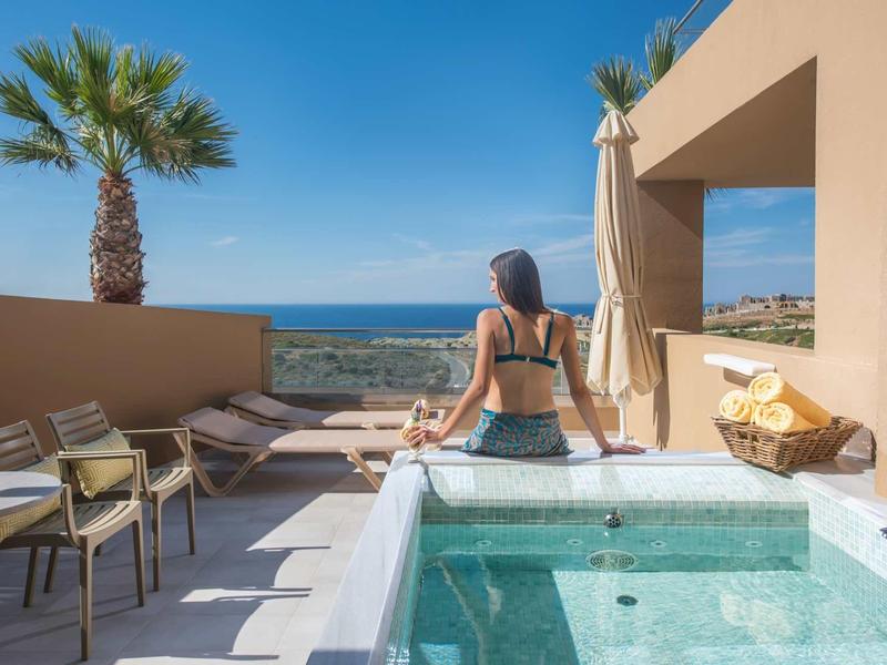 Femme regardant la mer et la silhouette urbaine depuis un balcon avec jacuzzi par beau temps.
