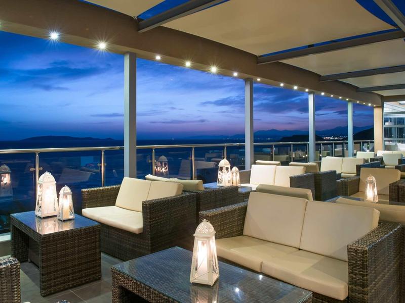 Salon confortable avec mobilier rembourré et lanternes sur une terrasse avec vue sur la mer au crépuscule.