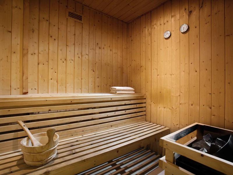 Sauna confortable avec bancs en bois, seau et louche, et poêle de sauna dans un hôtel.