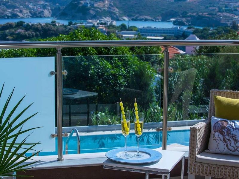 Balcon avec coin salon, vue sur une piscine et un paysage montagneux en arrière-plan.