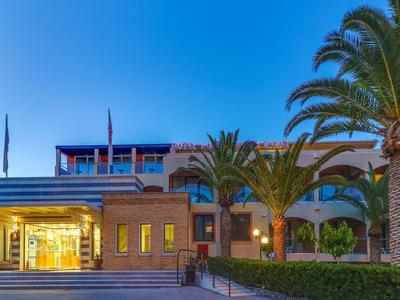 Budova hotelu s palmami a modrou oblohou za soumraku