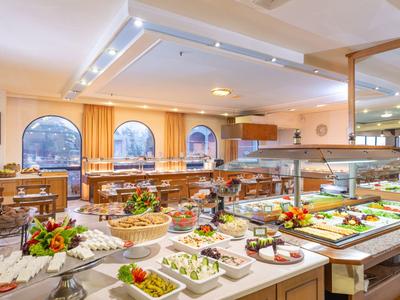 Světle osvětlená snídaňová místnost s rozmanitým bufetem a velkými okny