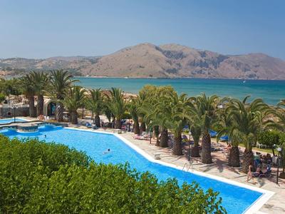 Piscina dell'hotel con palme e vista sul mare davanti a un'isola montuosa