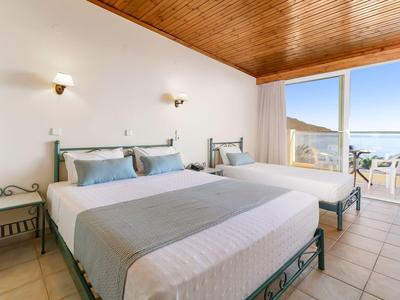 Camera luminosa arredata con due letti e balcone con vista mare.