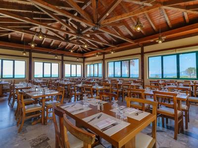 Ampia sala da pranzo dell'hotel con tavoli e sedie in legno e finestre panoramiche con vista sulle montagne.