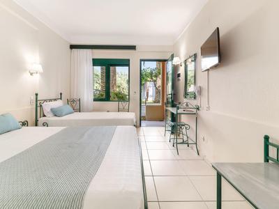 Jasný hotelový pokoj se dvěma postelemi a balkonem s výhledem.