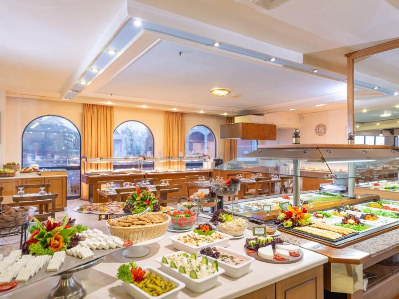 Světle osvětlená snídaňová místnost s rozmanitým bufetem a velkými okny