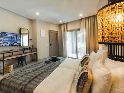 Habitación de hotel moderna con cama doble, espejo de pared y escritorio, iluminación suave.