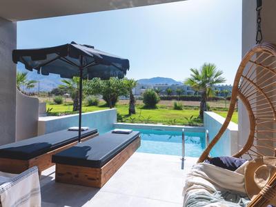Terraza con piscina, tumbonas y silla colgante con vistas a paisaje verde y montañas.